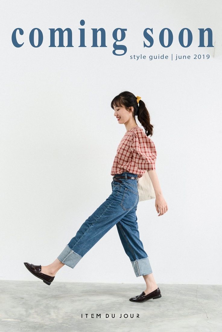 Woman in a plaid shirt and cuffed jeans walking against a white background