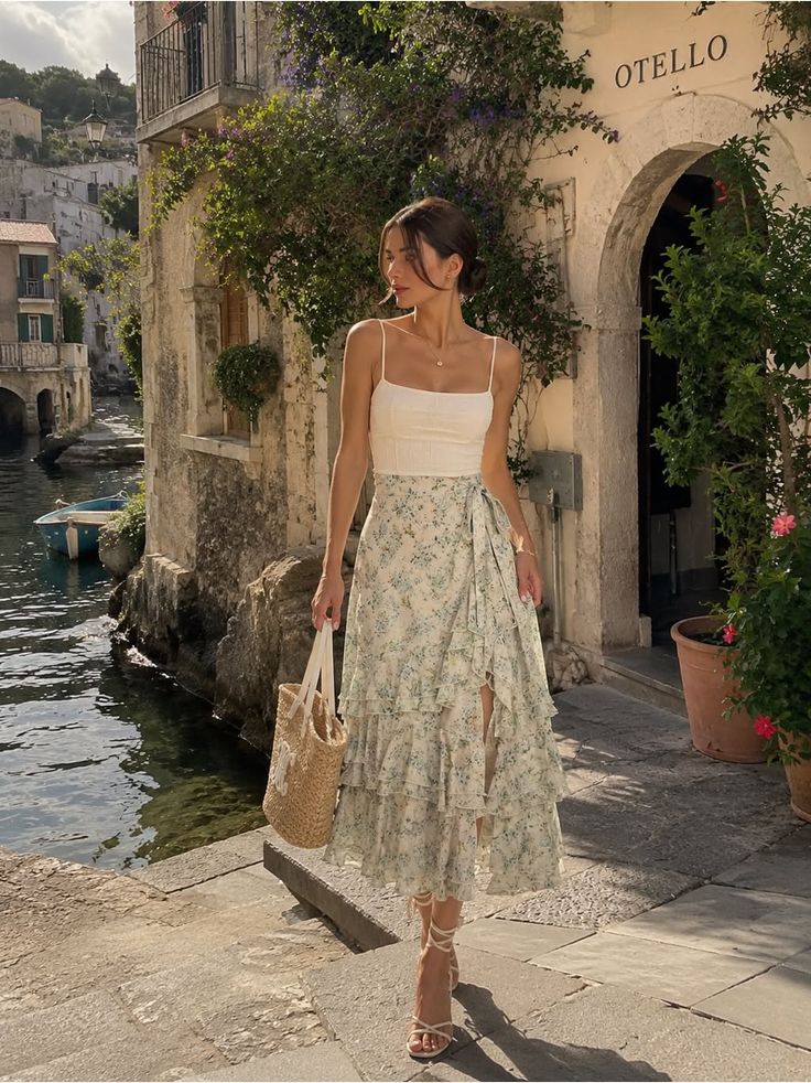 Woman in a floral ruffle skirt and white top walking in an old town by the water