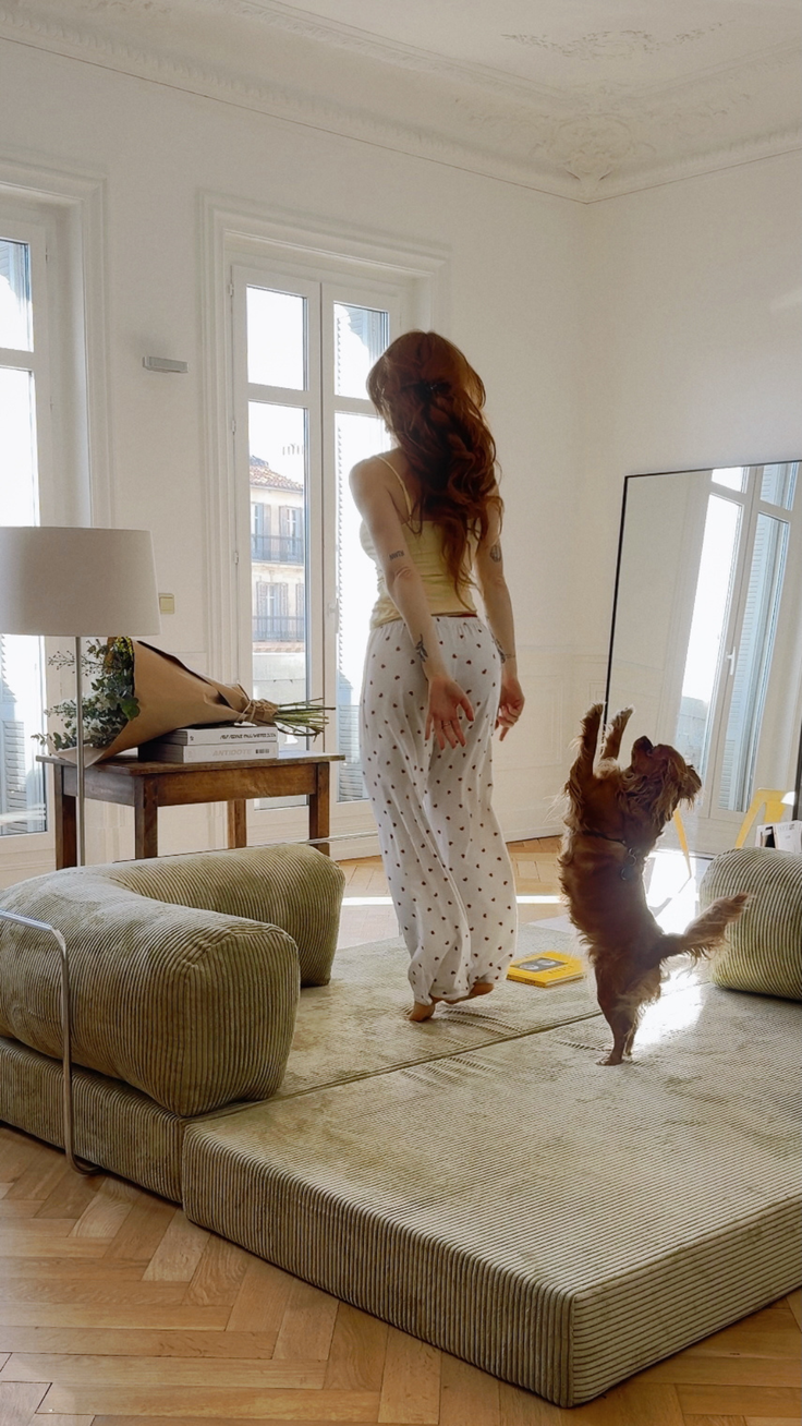 Woman with long red hair and a dog in a bright indoor setting