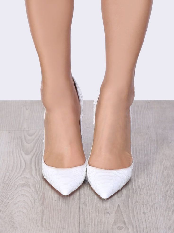 Person wearing white snake print high heels on a wooden floor