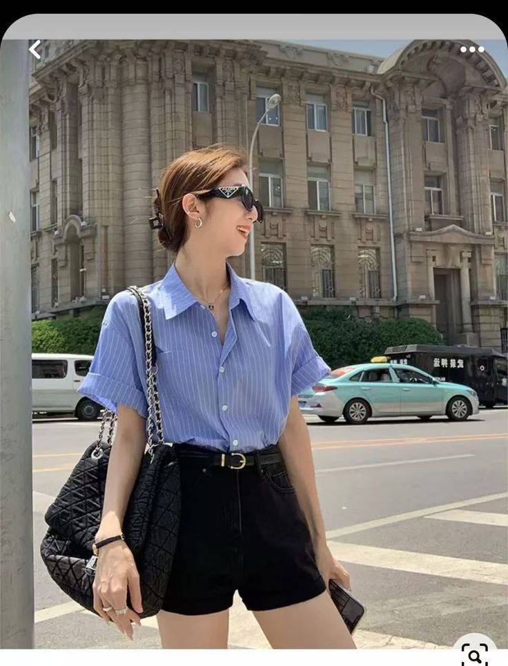 Woman in a blue striped shirt and black shorts on a city street