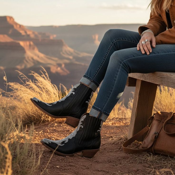 Person in cowboy boots and jeans sitting on a bench overlooking a canyon at golden hour