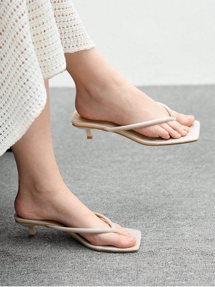 Woman's feet in beige kitten heel flip flops with a crochet dress
