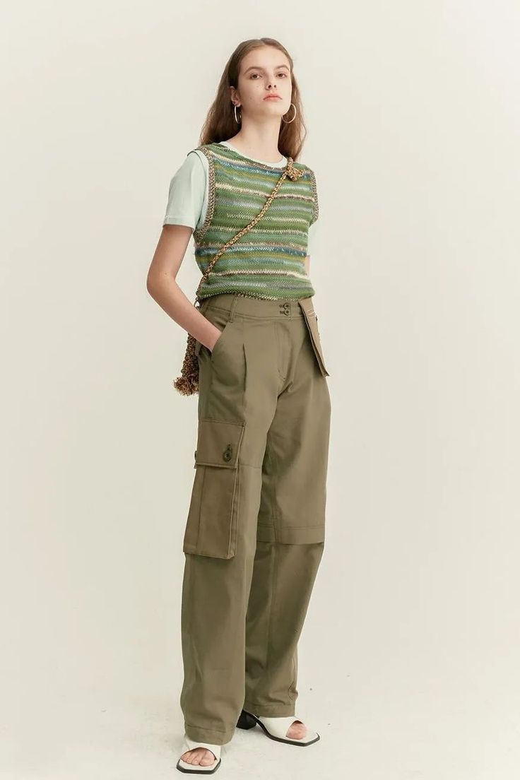 Woman in a knitted vest and cargo pants with hoop earrings in a studio