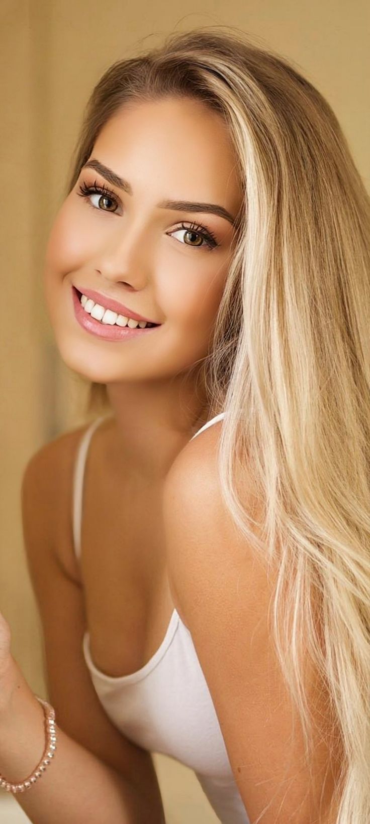 Smiling woman with long blonde hair wearing a white top