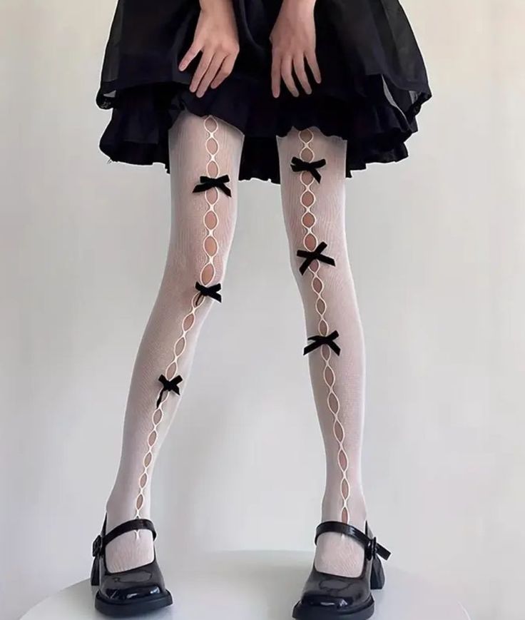 Person wearing white tights with black bows and a black dress
