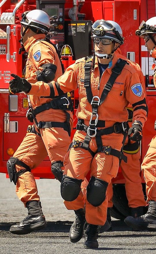 Rescue team members in orange uniforms and safety gear next to a fire truck