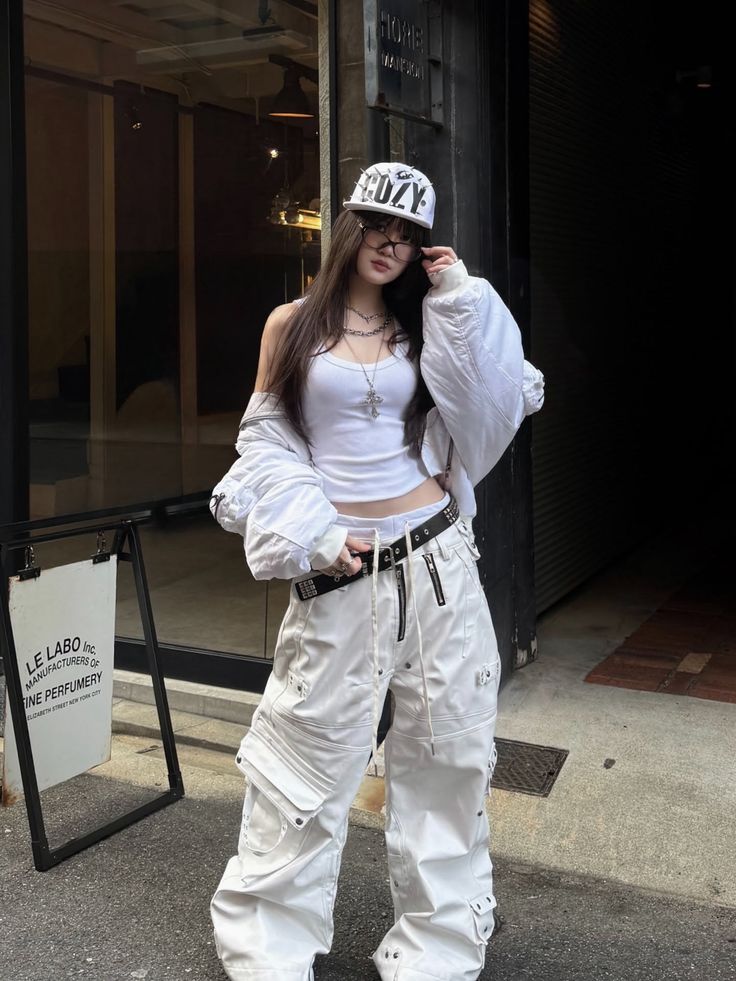 Woman in a white streetwear outfit with cargo pants and a baseball cap outdoors