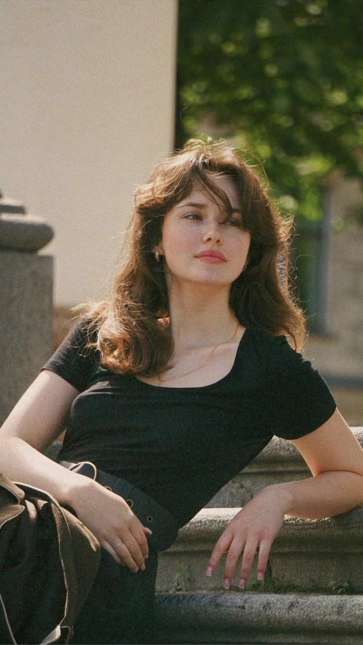 Woman with long brown hair and freckles in a black shirt outdoors