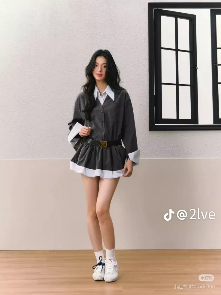 Woman with long dark hair wearing an oversized shirt and mini skirt indoors