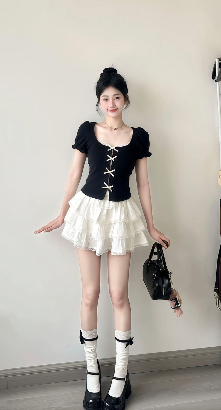 Woman in a black top and white tiered skirt with a black handbag