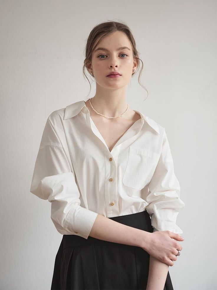 Woman in a white shirt and black skirt with an updo and pearl necklace