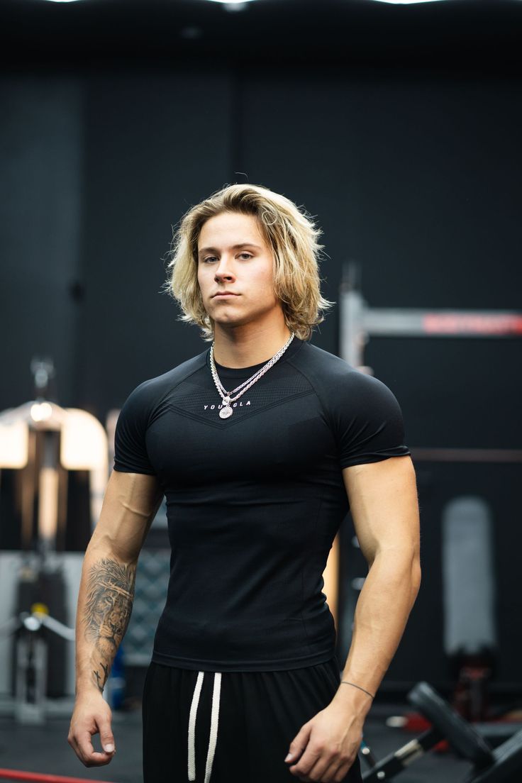 Muscular man with blonde long hair wearing a black t-shirt in a gym