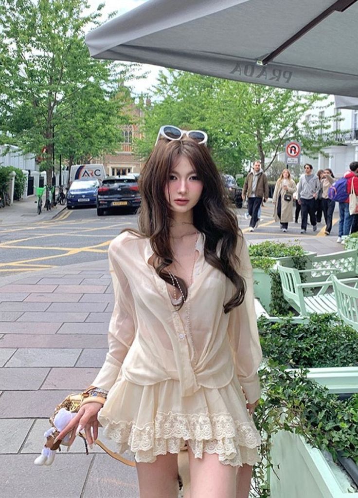 Woman in a sheer top and lace skirt on a street with people in the background