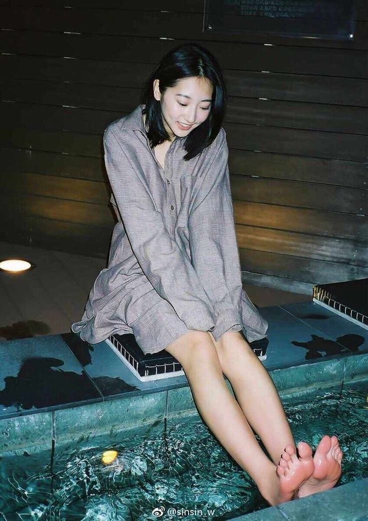 Woman with short hair sitting with her feet in water