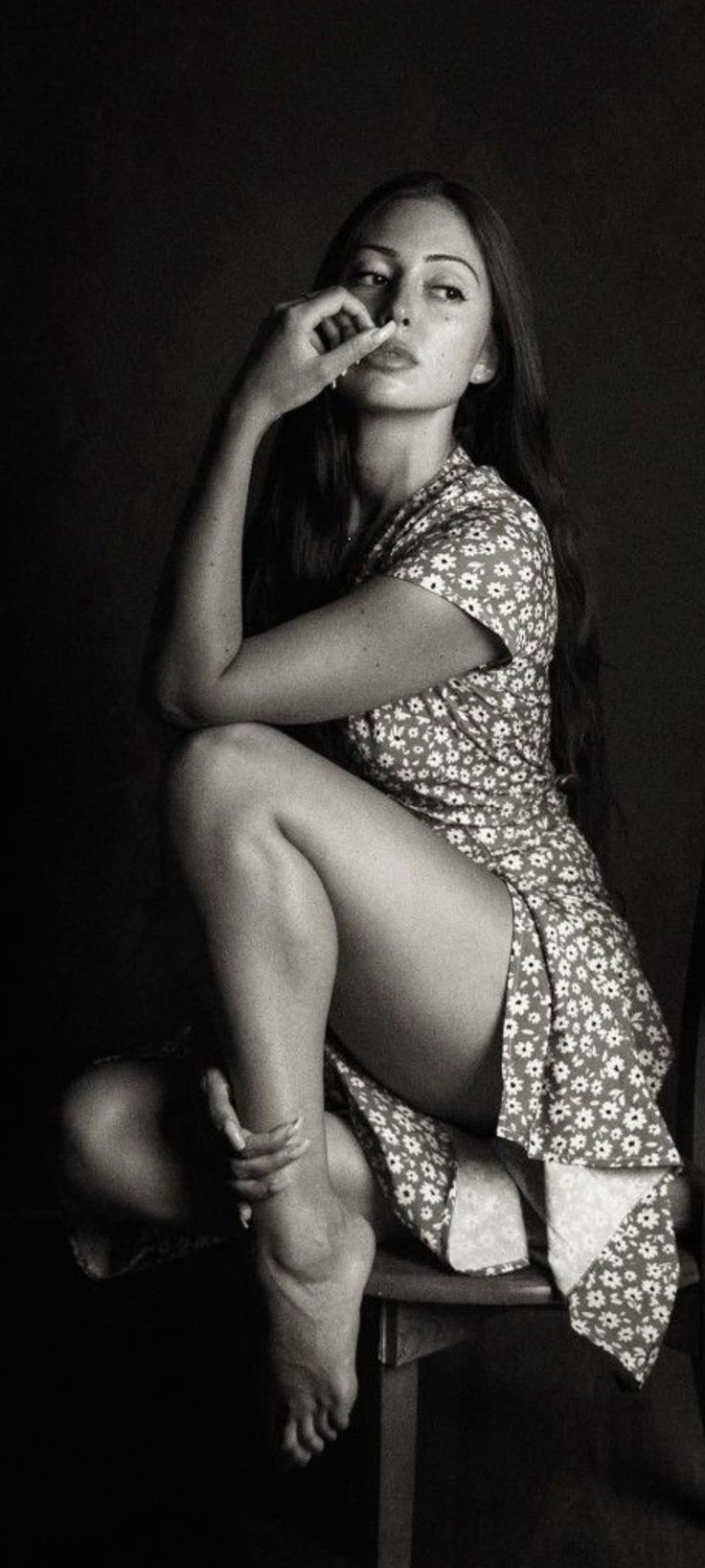 Woman in a floral dress with long hair, sitting in a dramatic pose
