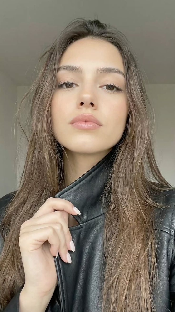 Woman with long brown hair wearing a black leather jacket