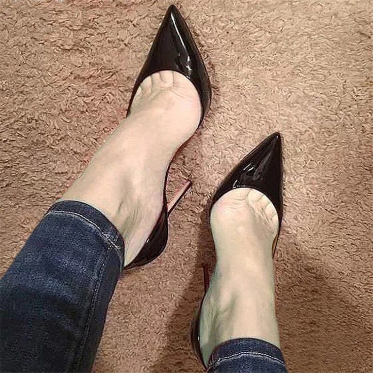 Person wearing black high heels and jeans on a brown carpet