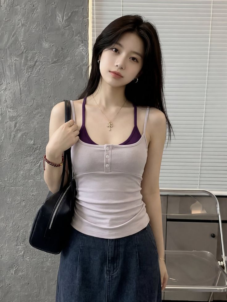 Woman with long black hair wearing a tank top and denim skirt indoors