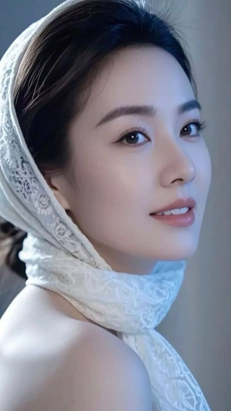 Woman with a white lace headscarf and exposed shoulder, looking at the camera