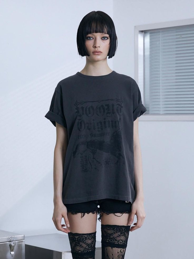 Woman with a short bob and bangs wearing an oversized t-shirt and lace stockings