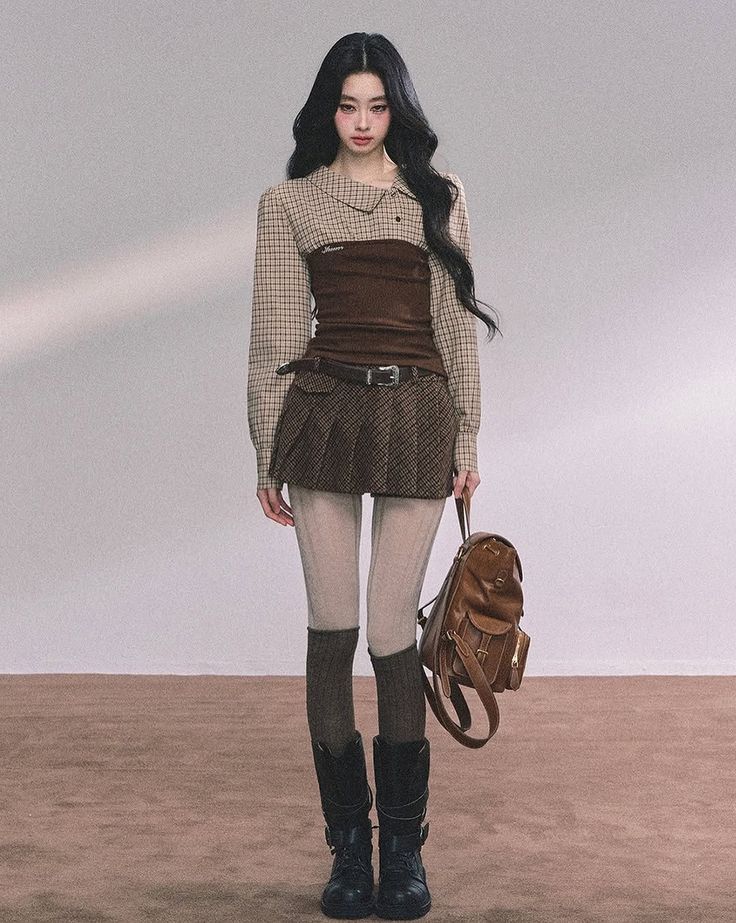 Woman with long black hair wearing a plaid shirt, corset top, and pleated skirt