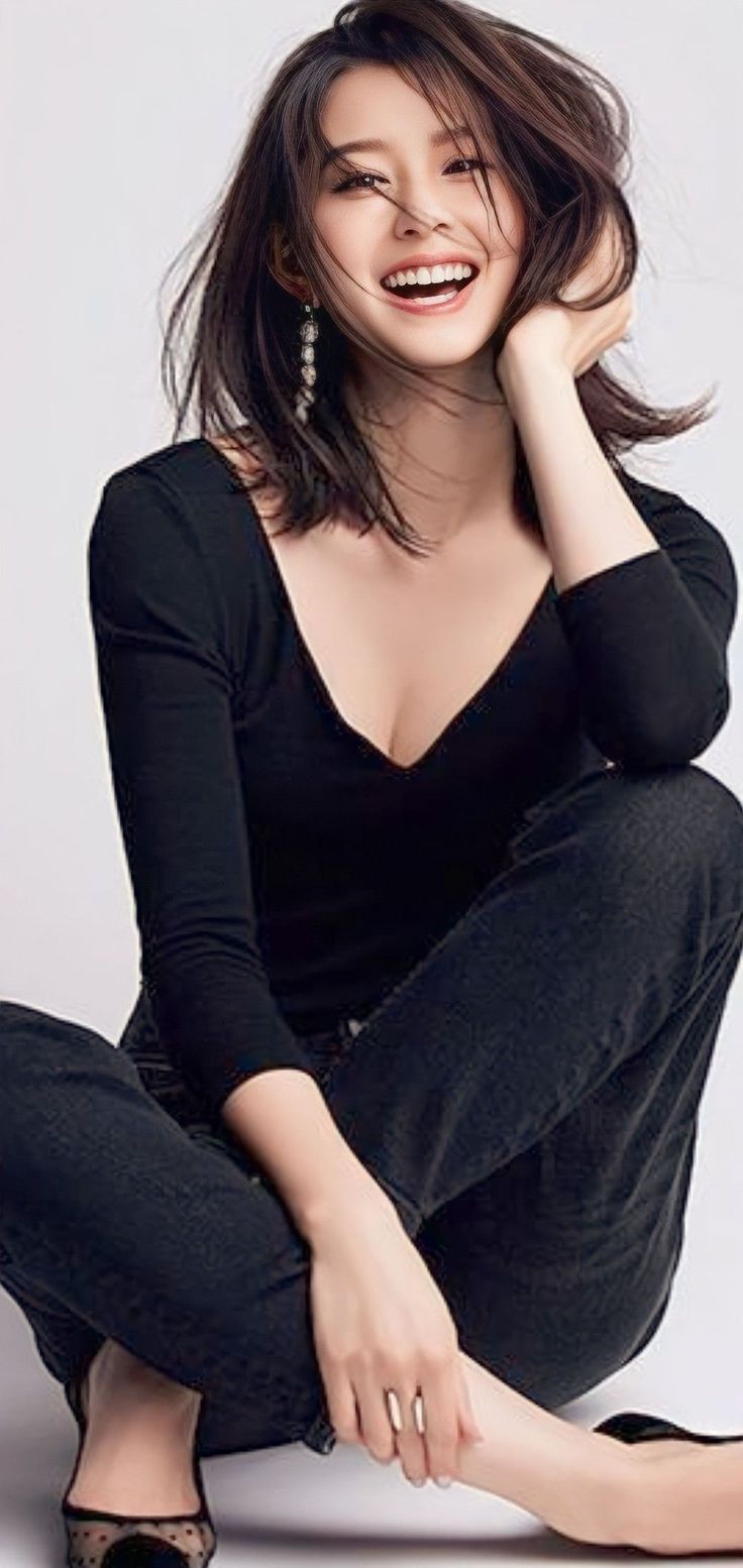 Woman with long hair and a black top sitting and smiling