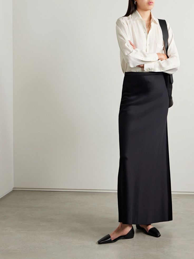 Woman in a long black skirt and white shirt with arms crossed