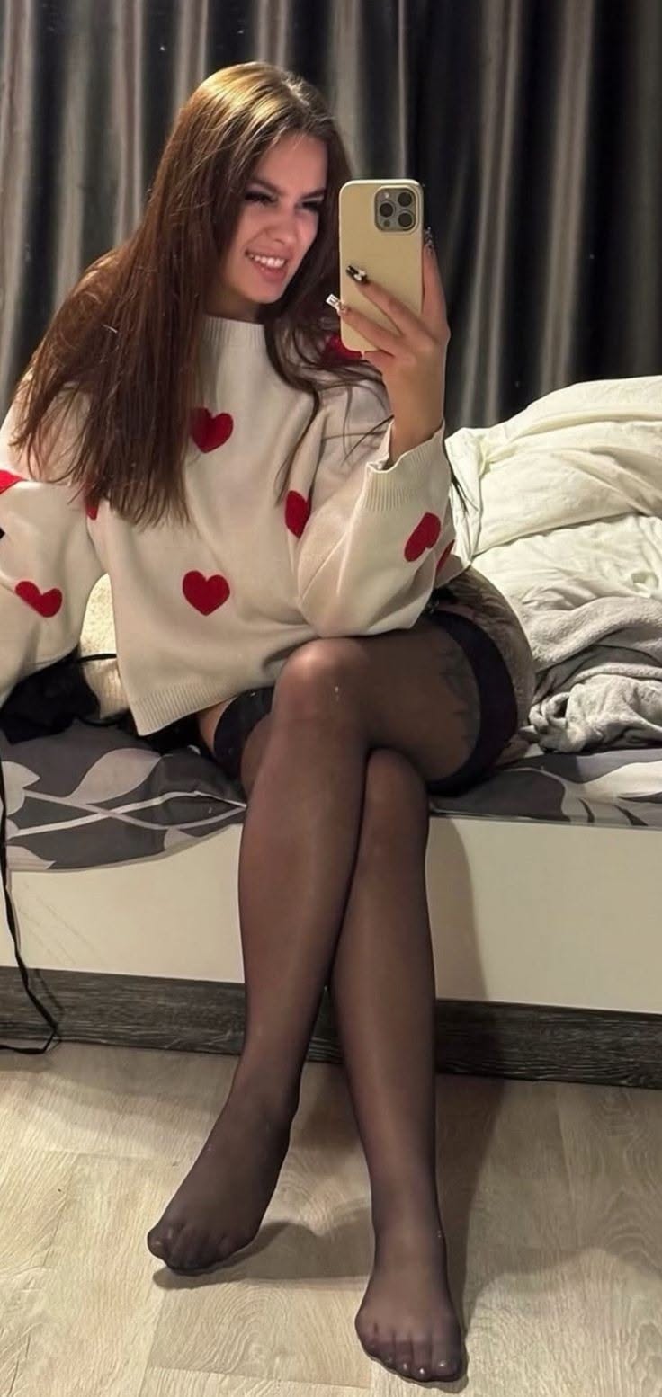 Woman in a heart print sweater and thigh high stockings taking a selfie