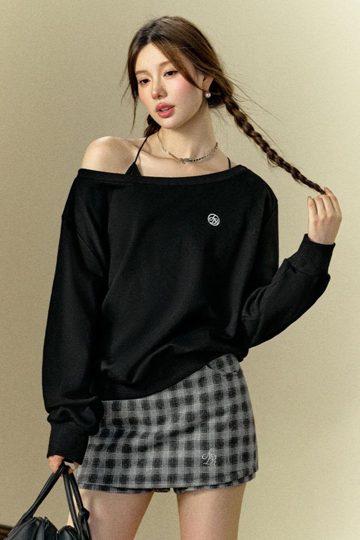 Woman with braids wearing an off-shoulder black top and plaid skirt