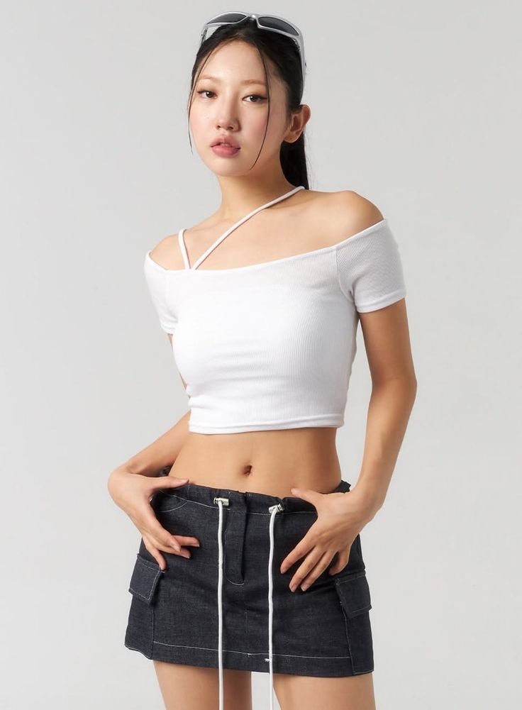 Woman in a white crop top and dark mini skirt with sunglasses on her head