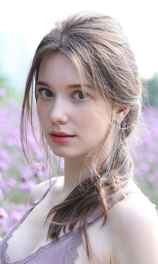 Woman with long hair and lace top in a field of purple flowers