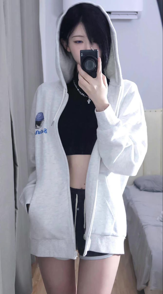 Person in a white hoodie and black crop top taking a mirror selfie