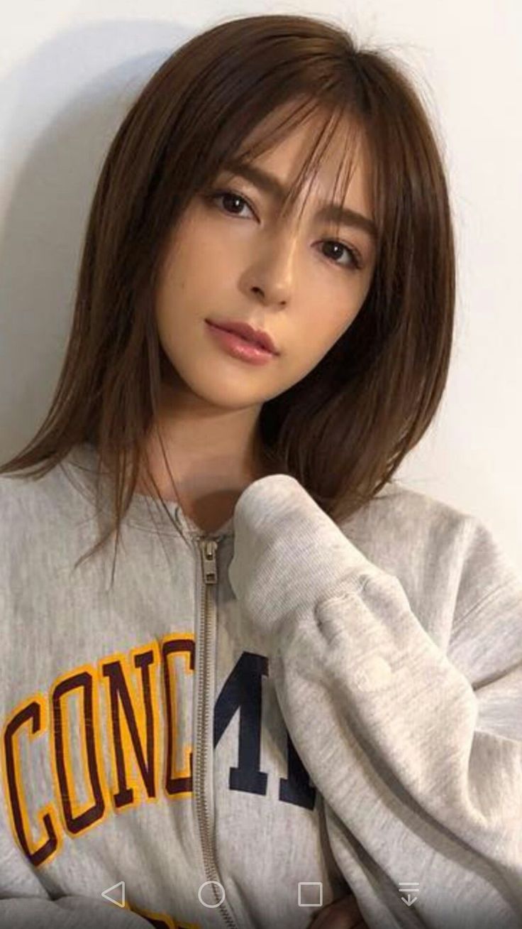 Woman with brown hair and bangs wearing a grey zippered hoodie