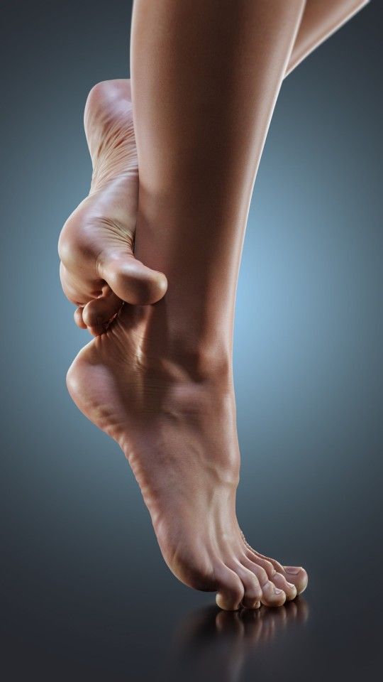 Close up of bare feet and legs against a dark background