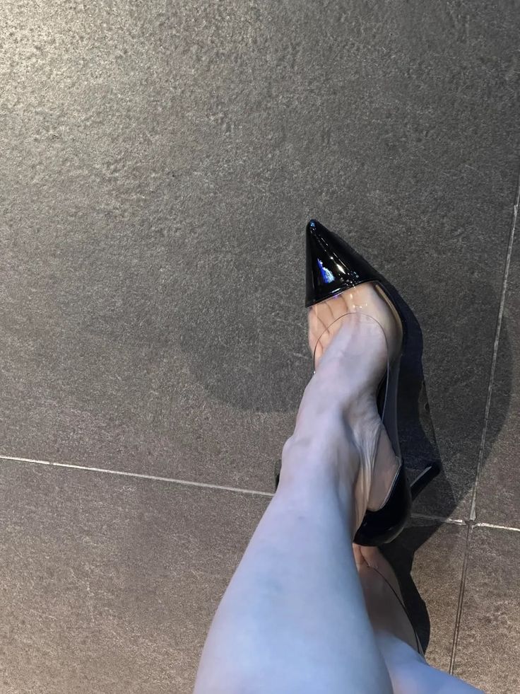 Person wearing black and clear high heels on a tiled floor