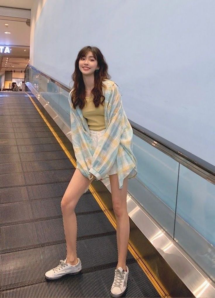 Woman with long hair wearing a plaid shirt and white shorts on an escalator