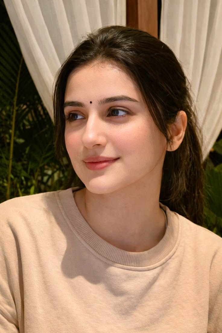 Woman with a bindi and ponytail wearing a beige sweatshirt outdoors