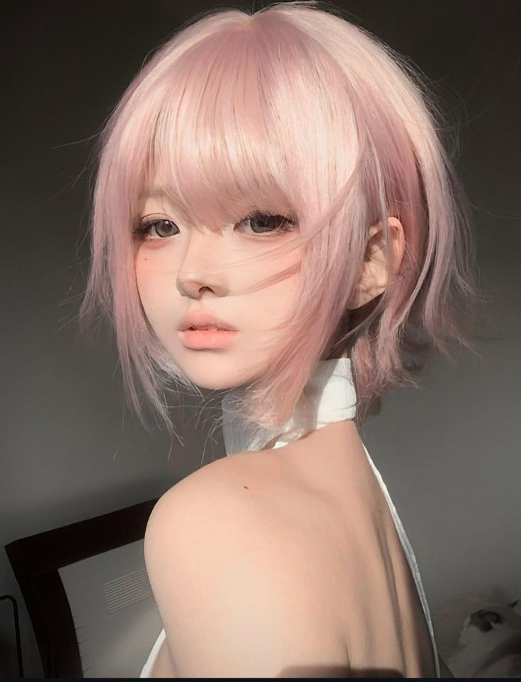 Woman with pink short hair and a white top looking over her shoulder