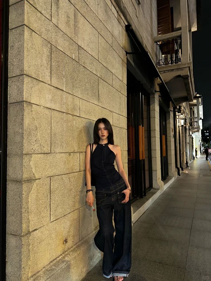 Woman in a denim halter top and wide leg jeans on a street at night
