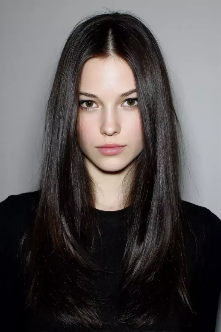 Woman with long dark hair wearing a black shirt in a studio portrait
