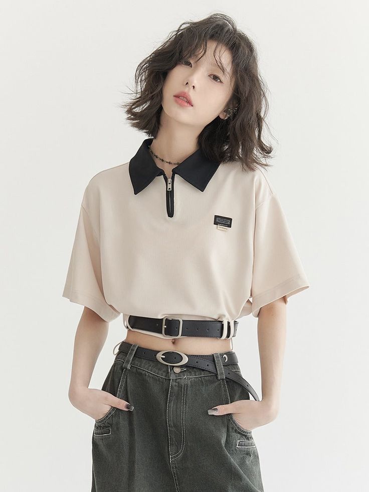 Woman with short hair wearing a cropped polo shirt and dark jeans