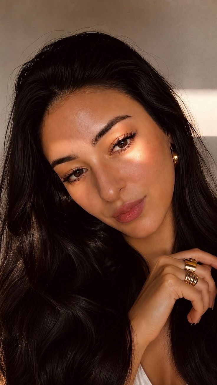 Woman with long black hair and gold jewelry in soft golden hour lighting