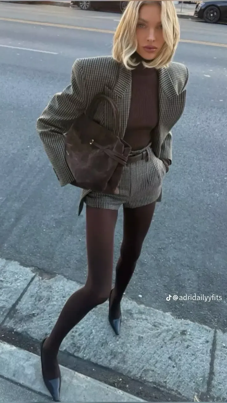 Woman in a striped blazer and shorts with tights and heels outdoors