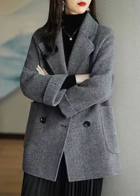 Woman in a gray coat and black turtleneck with arms crossed