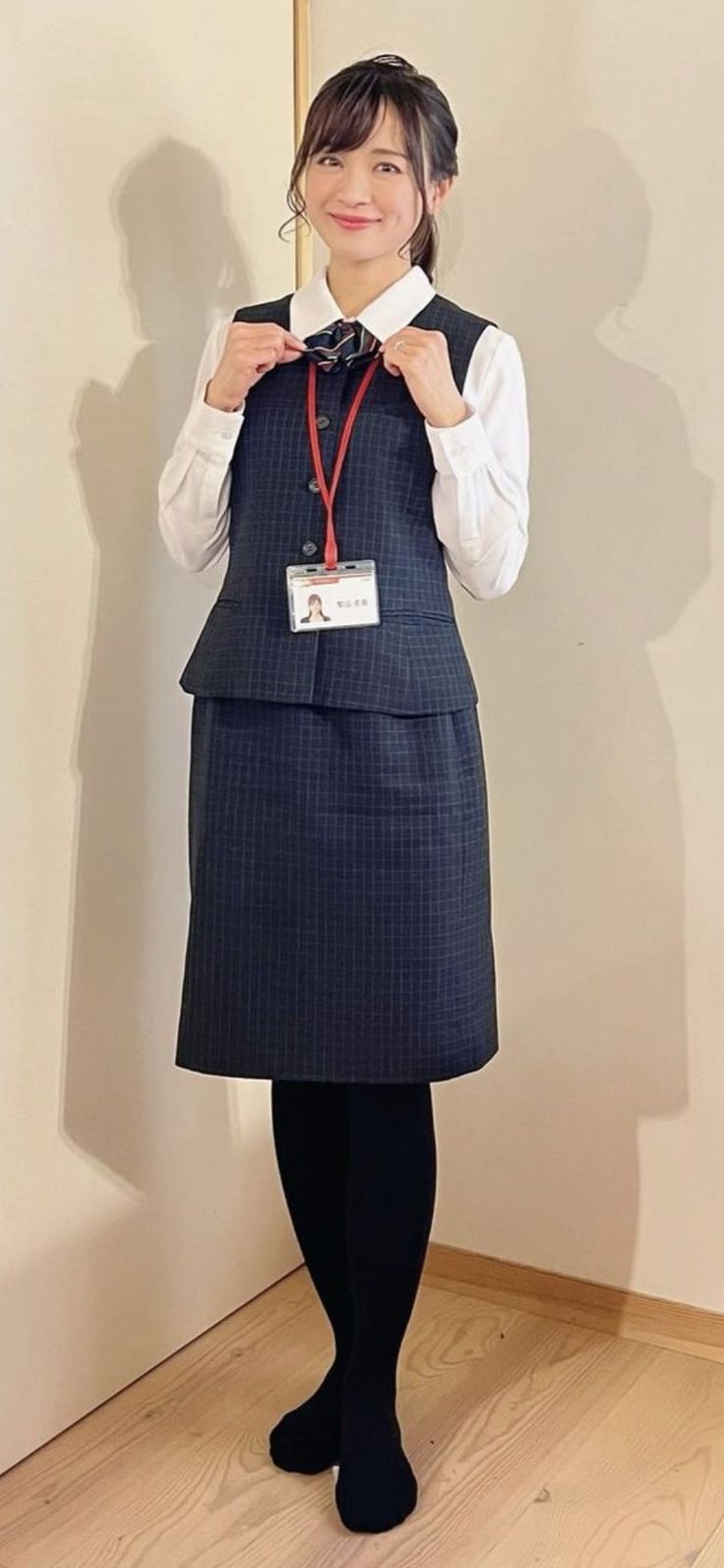 Woman in business attire with an ID badge, standing indoors
