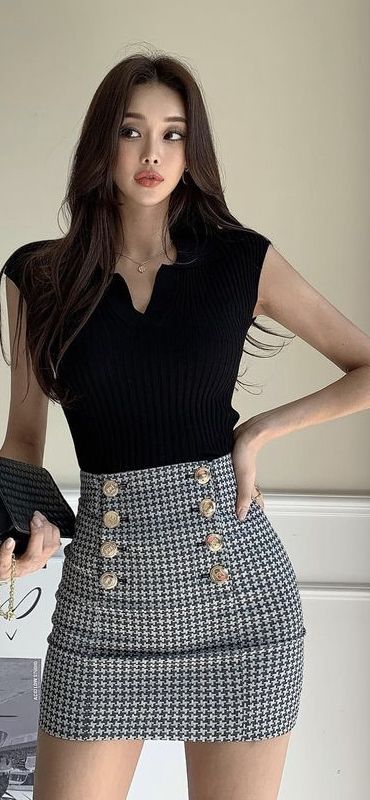 Woman with long hair wearing a black top and houndstooth mini skirt