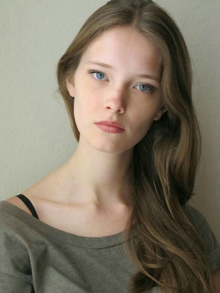 Woman with long brown hair and blue eyes wearing an off-shoulder top