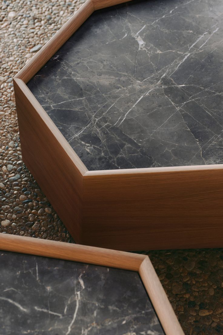 Close up of a hexagonal marble top table with a wooden frame on pebble ground