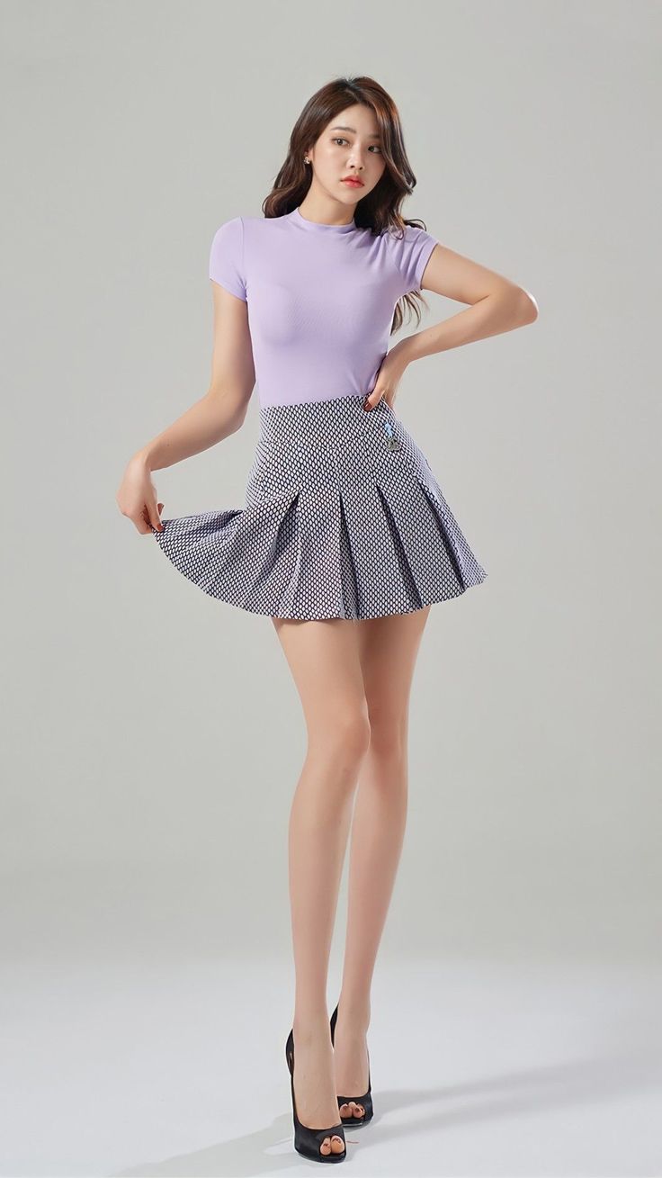 Woman in a purple top and pleated skirt posing in a studio